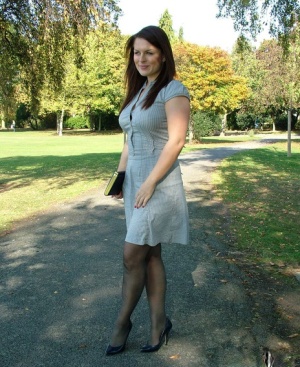 Clothed woman shows off her nylon ensconced legs and pumps in the park