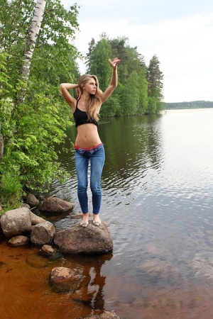 Girl next door Megan pulls out her tits while sitting on a rock in the lake
