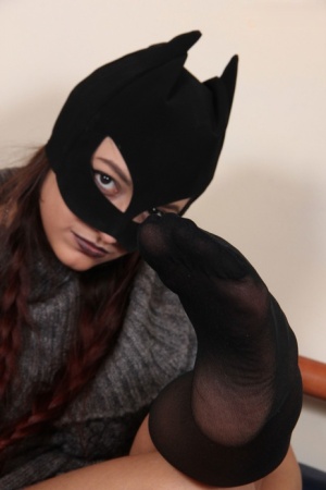 Clothed female Ladynight sports a mask while taking off her boots and socks