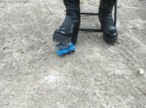 Unknown female crosses a dinky toy into the ground with black leather boots