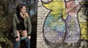 Short taken girl pulls down her jeans to take a piss by a brick building