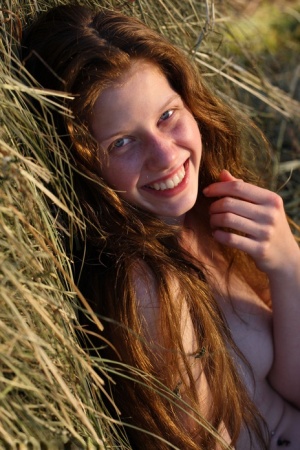 Young girl with long red hair and a tight butt poses nude against stooped hay 53451013