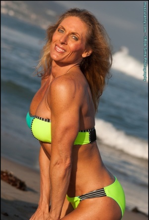 Female bodybuilder Kimberly Dickson poses in a bikini while at the beach