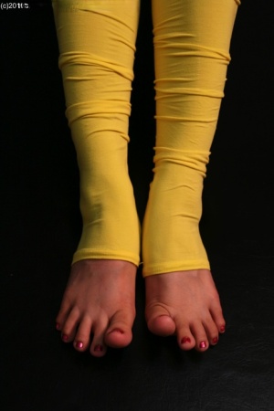 Caucasian female plays with her feet while wearing yellow leg warmers 94942296