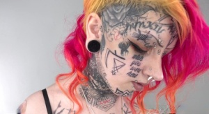 Solo girl with dyed hair Mami displays her heavily tattooed body in a bikini