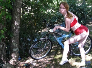 Young redhead Nicki Blue somewhat pulls down her shorts on top of her bicycle