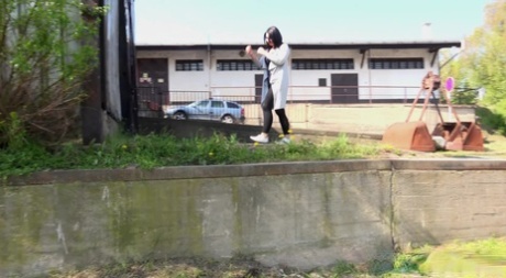 Dark-haired chick Lora pulls down her leggings to pee over a retaining wall