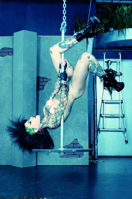 Heavily tattooed goth Malice performs a nude pole dance in high-heeled boots