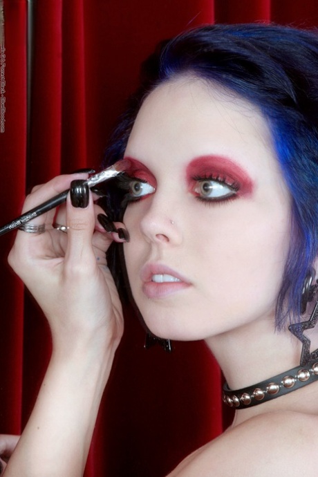 Goth girl Sara X does her eye makeup in a mirror while topless 50609177