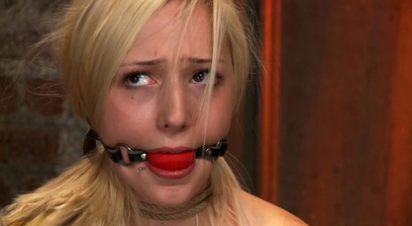 Blonde girl is fitted with a ball gag after being forced into bondage 77390195