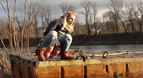 Blonde girl Debora squats to take a piss down by a river