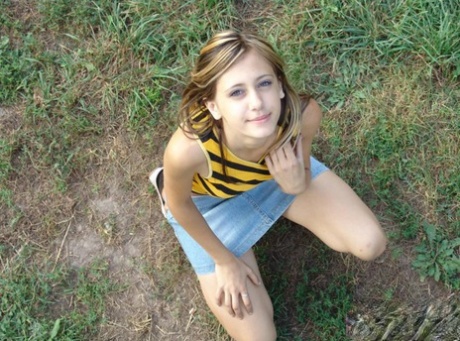 Young cutie in denim mini skirt cavorting and romping on the grass 82950424