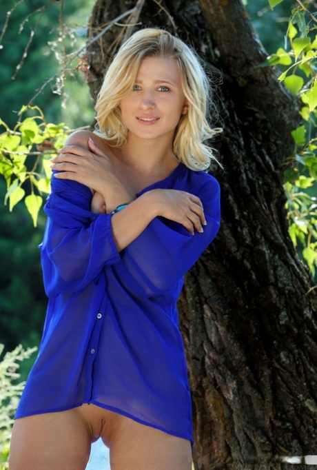 Petite blond teen Lisa Dawn delights in displaying her tight slit under a tree