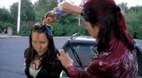 Clothed women douse each other in food products at a drive-in car wash 13202210