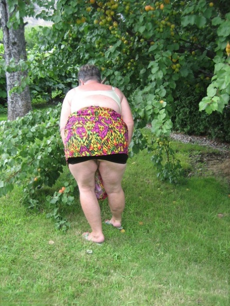 Fat granny Girdle Goddess exposes her large tits under a fruit bearing tree 69058538