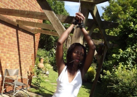 Black girl is cleaved gagged and bound with her hands above her head in a yard 32320395