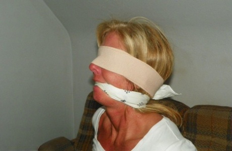 Blonde female is tied up with rope after being blindfolded and gagged 44386286