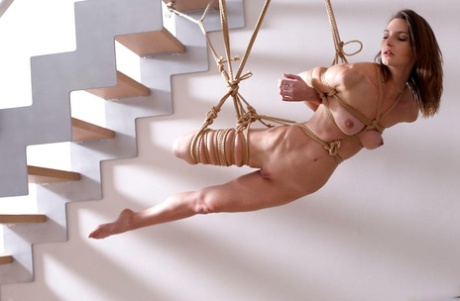 Naked white girl is suspended in midair by ropes with no one else around 97859276