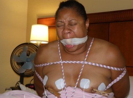 Ebony fatty receives electrical shocks while tied up and gagged on a bed 46615722