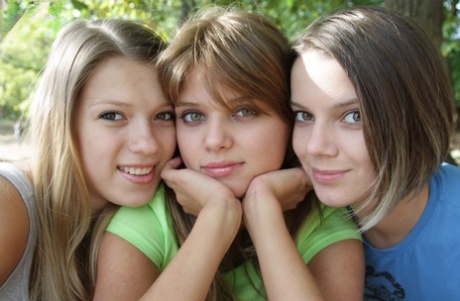 Three young looking girls gets naked on a wooden bench in the countryside 11023364