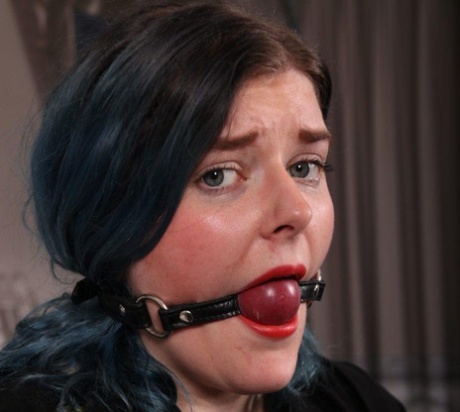 Brunette female sports a ball gag while restrained with black leather belts 95120805