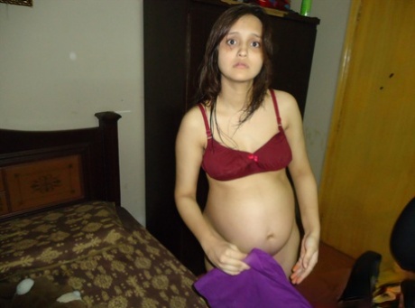 Pregnant Indian girl moisturizes after a shower before getting dressed 77442676