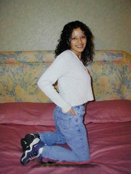 Latina girl with curly hair shows her bare ass on top of a bed