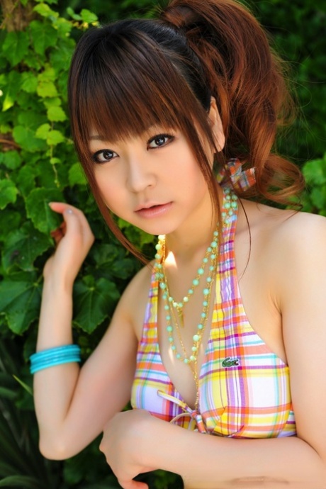 Tiny Asian girl wears her hair in a ponytail while modeling a bikini by a pool 89323523