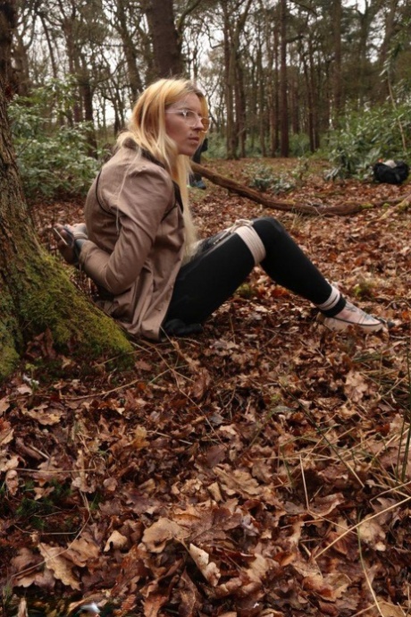 Glasses wearing woman in tied with ropes to a treed in woods with clothes on 89420316