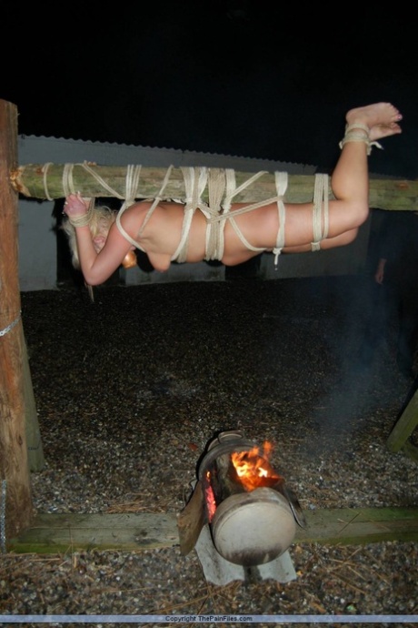 Naked blonde with an apple in her mouth is roasted over a fire while rope tied 37734725