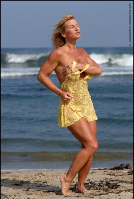 Muscular blonde Peggy Vee frees her fake tits from a yellow dress at the ocean 19005250