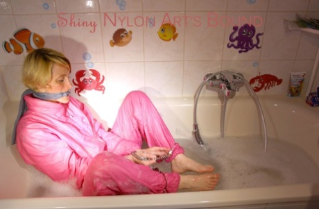 Blonde girl is left alone in a tub of bathwater while restrained in nylon wear 88594020