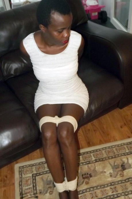 Black female is left tied and cleave gagged in a white dress on a leather sofa 65679458