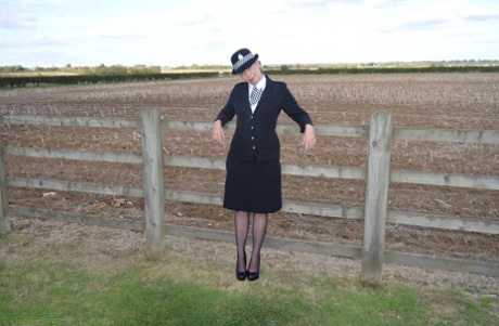 Mature policewoman Barby Slut removes her uniform against a fence at a farm 31055216