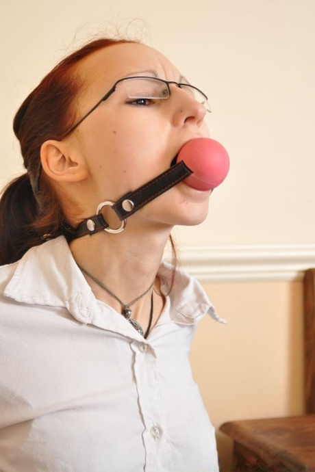 Geeky redhead sports a big ball gag while restrained in chains 83739213