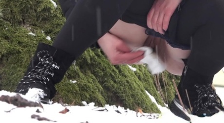 Blonde girl Masha pees on snow-covered ground against an old tree 64692227