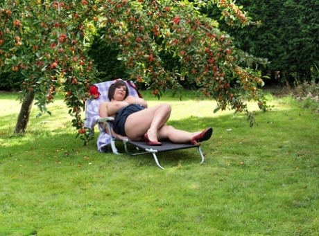 Plump amateur Roxy displays her huge boobs and bald cunt under a fruit tree