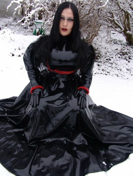 Goth woman Lady Angelina models a black latex dress on snow-covered ground 26674228