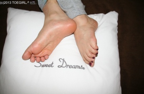 Caucasian female displays her bare feet over a pillow in sweat pants 35432546