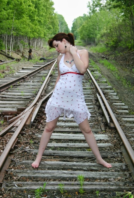 Redheaded girl Barbie A models a summer dress in bare feet on railway tracks 58908497