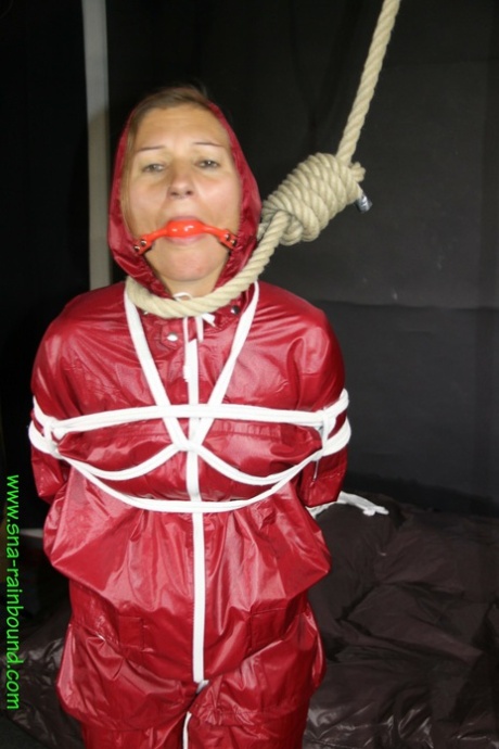 Restrained female Sandra is fitted with a ball gag and noose in a raincoat 14762655