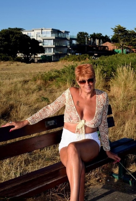 Mature redhead Dimonty exposes her sagging tits on a bench down by the sea 97548182