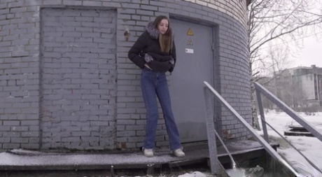White girl pulls down her jeans to pee in the snow behind a building 95208221