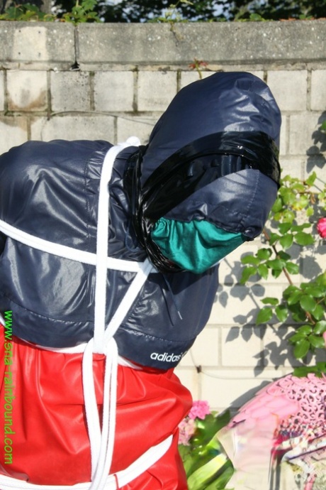 Submissive woman Sandra is tied up while wearing a raincoat in a sunny yard 11654570