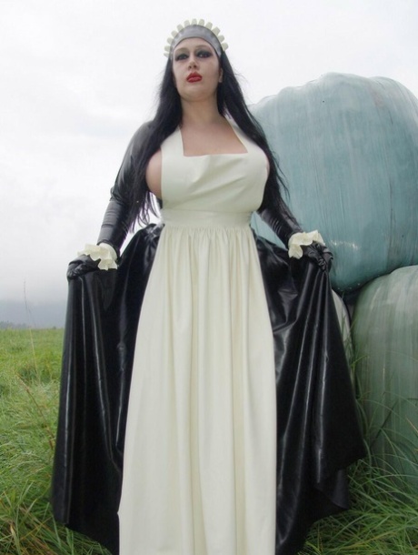 Goth woman Lady Angelina does her laundry outdoors in a tub in latex clothing 46816296