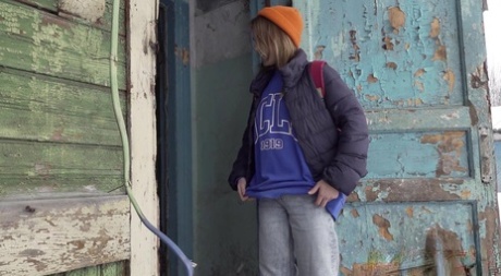 Cute girl pulls down jeans for an urgent piss on the steps of an old building 97606401