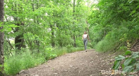 Caucasian girl Julia North pulls down leggings to pee on a path in the woods 96477424