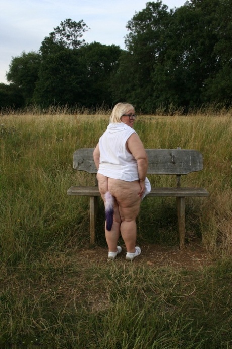 Fat British lady Lexie Cummings exposes herself on a bench in a field 73928782