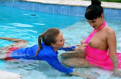 Fully clothed women partake in lesbian foreplay while in a swimming pool 70031378