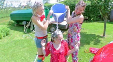 Young girls soak each other in a backyard while washing a compact vehicle 13984560